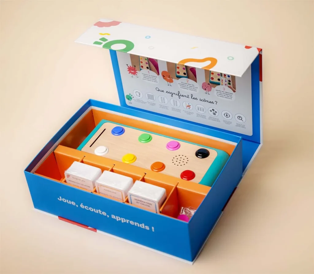 Photographie de la boite Koolookoo avec son contenu. Station de jeu avec cartes