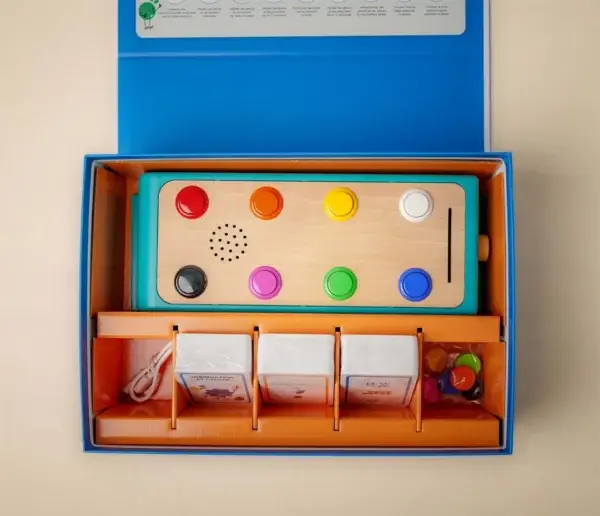 Boîte du jeu Koolookoo ouverte montrant la station éducative, les cartes d’activités et les pions colorés.